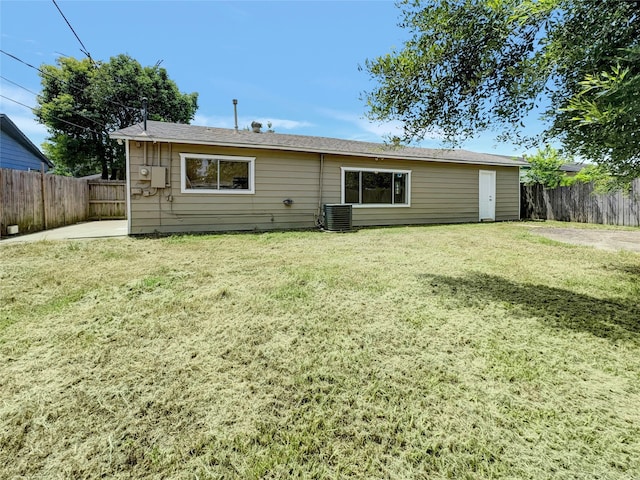 back of house featuring central AC unit and a lawn