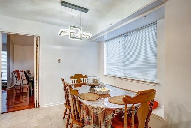 tiled dining room featuring an inviting chandelier and a healthy amount of sunlight