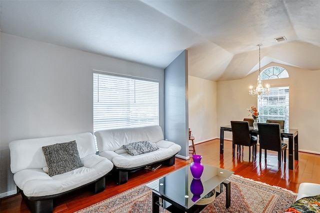 living room with hardwood / wood-style flooring, vaulted ceiling, and an inviting chandelier