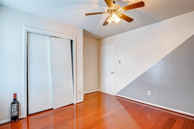 unfurnished bedroom featuring ceiling fan, hardwood / wood-style flooring, and a closet