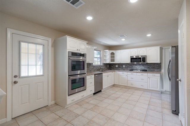 kitchen with decorative backsplash, stainless steel appliances, sink, and white cabinets