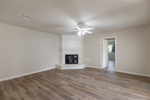 unfurnished living room featuring hardwood / wood-style flooring, a brick fireplace, and ceiling fan