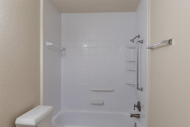 bathroom featuring tiled shower / bath combo and toilet