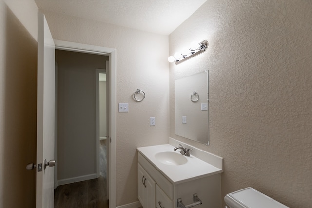 bathroom with hardwood / wood-style flooring, toilet, and vanity