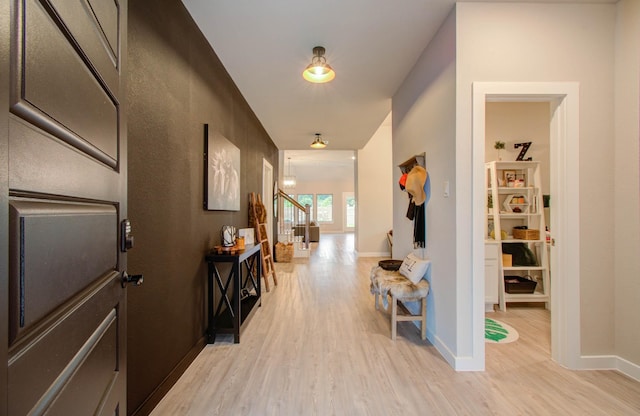 hall featuring stairs, baseboards, and light wood-style floors