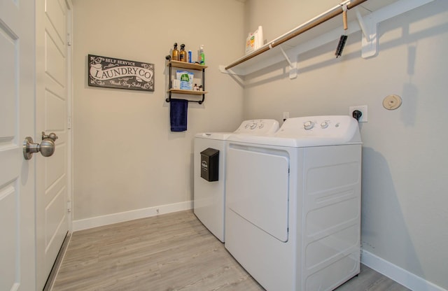 clothes washing area with laundry area, light wood-style flooring, baseboards, and washer and dryer