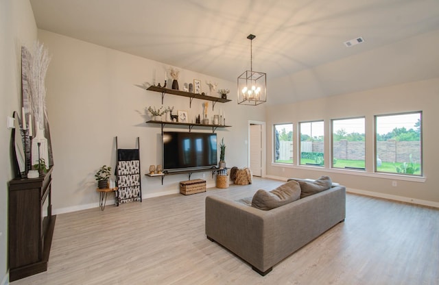 living room featuring a chandelier, light wood finished floors, visible vents, and baseboards