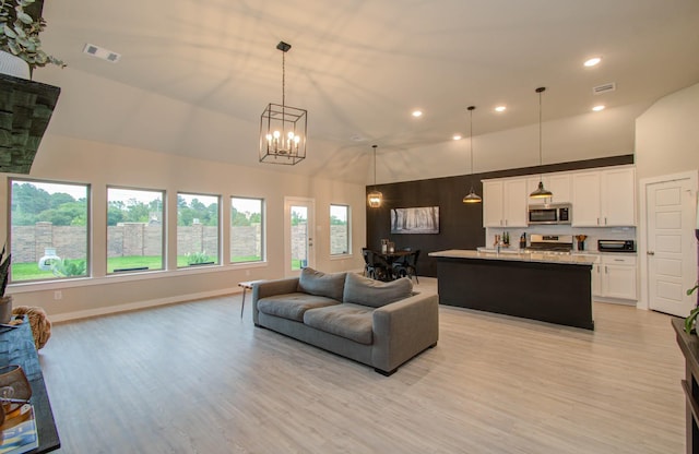 5727 Daylight Cv, Fulshear, TX 77441 - living room with high vaulted ceiling, recessed lighting, light wood-type flooring, healthy amount of natural light, and a chandelier