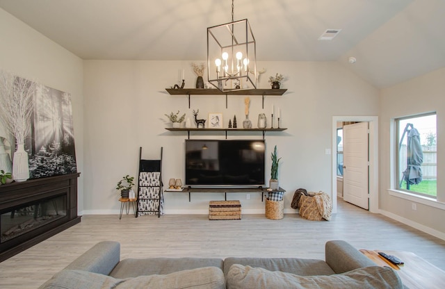 living room featuring lofted ceiling, visible vents, a notable chandelier, and wood finished floors