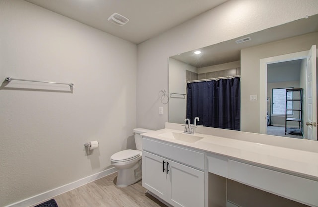 bathroom with visible vents, vanity, toilet, and wood finished floors