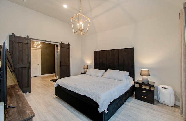 bedroom with a barn door, baseboards, lofted ceiling, light wood-type flooring, and a notable chandelier