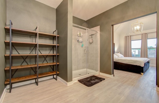 full bathroom with a stall shower, wood finished floors, baseboards, and ensuite bathroom