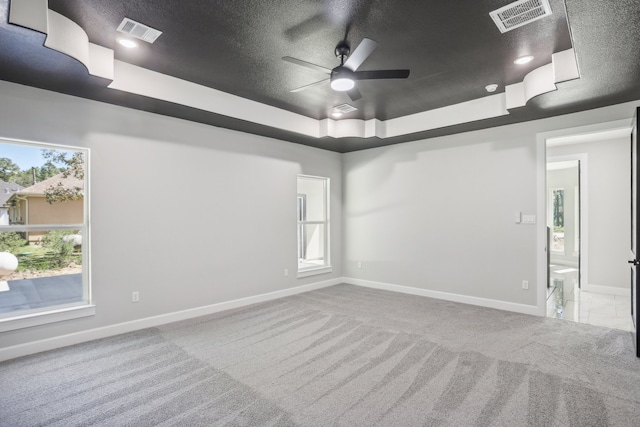 carpeted spare room with ceiling fan, a raised ceiling, and a textured ceiling