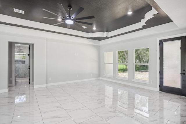 empty room with ceiling fan, a textured ceiling, and a raised ceiling