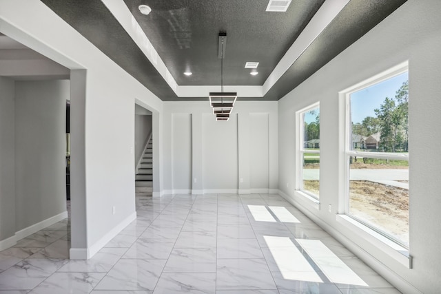 interior space with a textured ceiling and a tray ceiling