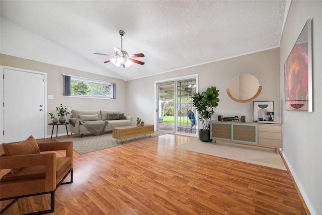 living room with a textured ceiling, wood-type flooring, a healthy amount of sunlight, and vaulted ceiling