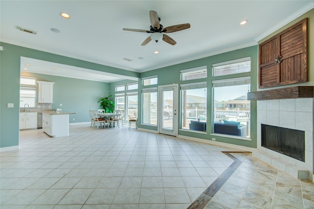 unfurnished living room featuring a healthy amount of sunlight, a fireplace, sink, and light tile patterned floors