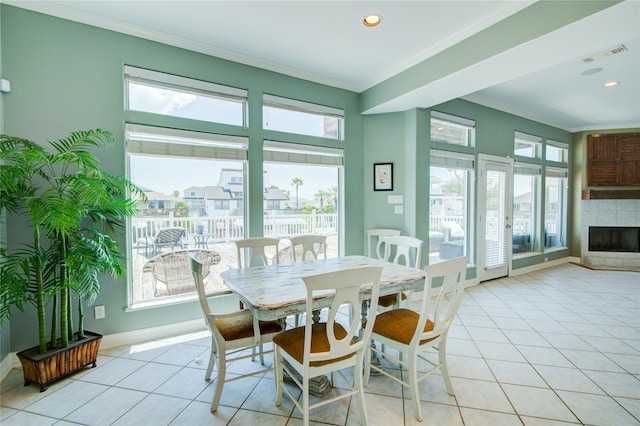 dining space with light tile patterned flooring, a fireplace, and crown molding