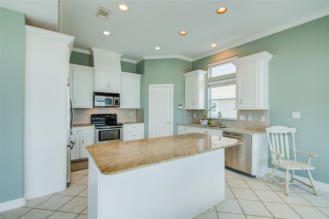 kitchen featuring a center island, sink, light stone countertops, white cabinetry, and stainless steel appliances