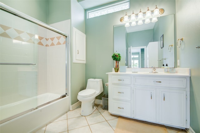 full bathroom with bath / shower combo with glass door, vanity, tile patterned floors, and toilet