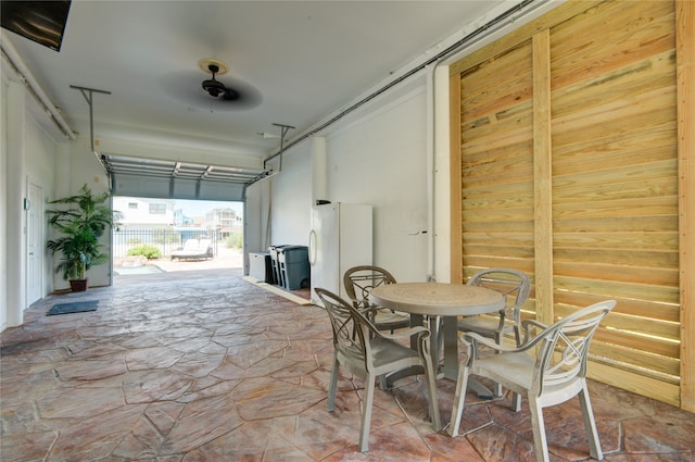 garage with white fridge, ceiling fan, and wooden walls