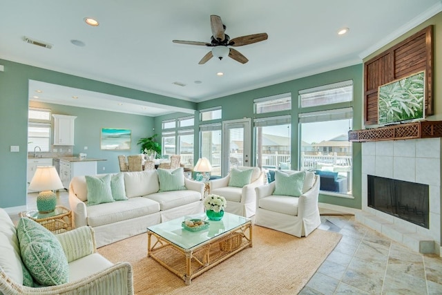 living room featuring ornamental molding, plenty of natural light, a fireplace, and sink