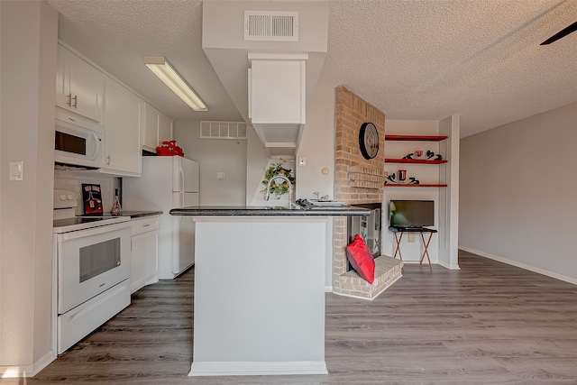 kitchen featuring a textured ceiling, hardwood / wood-style floors, white appliances, and white cabinetry