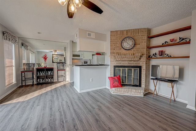 unfurnished living room with ceiling fan, a fireplace, and hardwood / wood-style floors