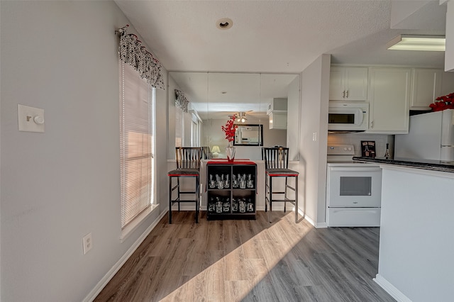 kitchen with white appliances, light hardwood / wood-style floors, and white cabinetry