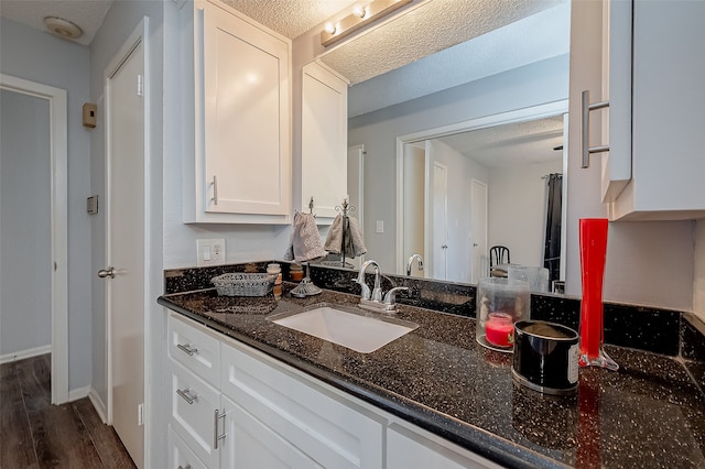 interior space featuring white cabinets, sink, a textured ceiling, dark hardwood / wood-style floors, and dark stone countertops