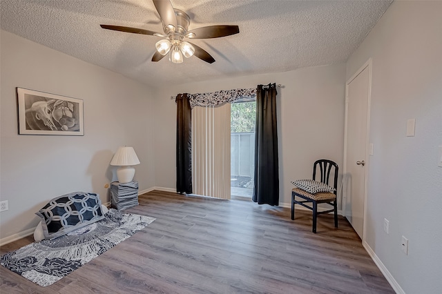 living area with light hardwood / wood-style floors, ceiling fan, and a textured ceiling