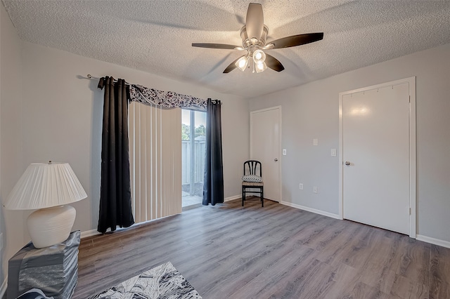 interior space with light wood-type flooring, ceiling fan, and a textured ceiling