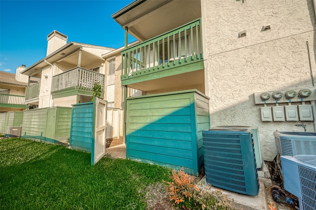 view of side of home featuring a balcony, a yard, and central AC