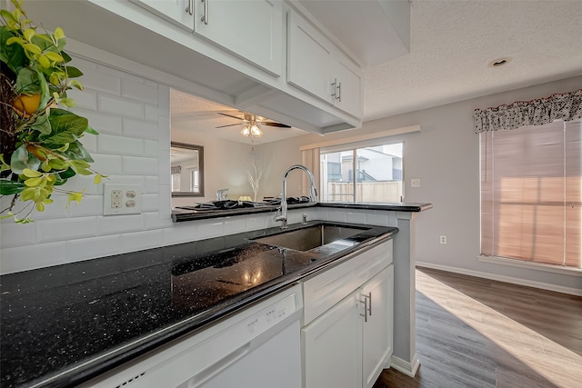 kitchen with dark stone counters, white cabinets, a textured ceiling, and sink