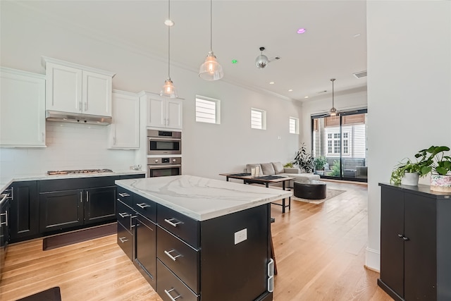 kitchen featuring backsplash, white cabinetry, light hardwood / wood-style floors, and double oven