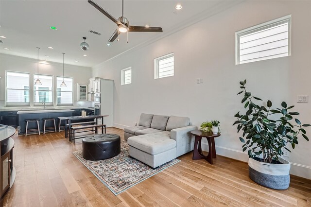 living room with light hardwood / wood-style flooring, a wealth of natural light, and ceiling fan