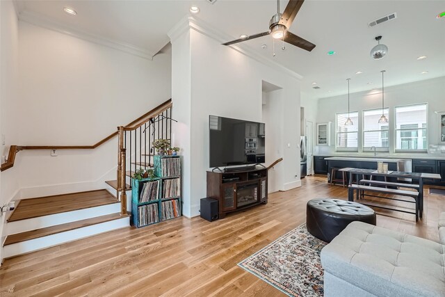 living room with sink, crown molding, ceiling fan, and light hardwood / wood-style floors