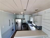 kitchen with white cabinets, stainless steel refrigerator with ice dispenser, decorative light fixtures, and kitchen peninsula