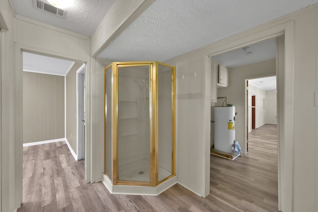 bathroom with a shower with door, a textured ceiling, gas water heater, and hardwood / wood-style flooring