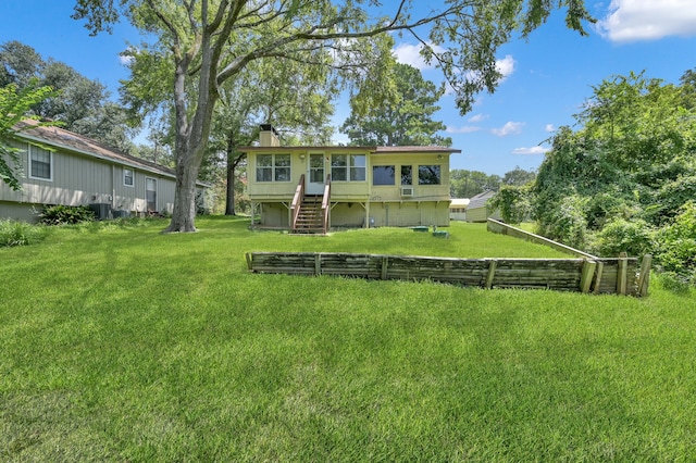 rear view of house with central AC unit, a yard, and a wooden deck