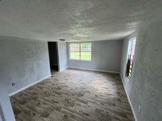 unfurnished room featuring dark hardwood / wood-style flooring and a textured ceiling