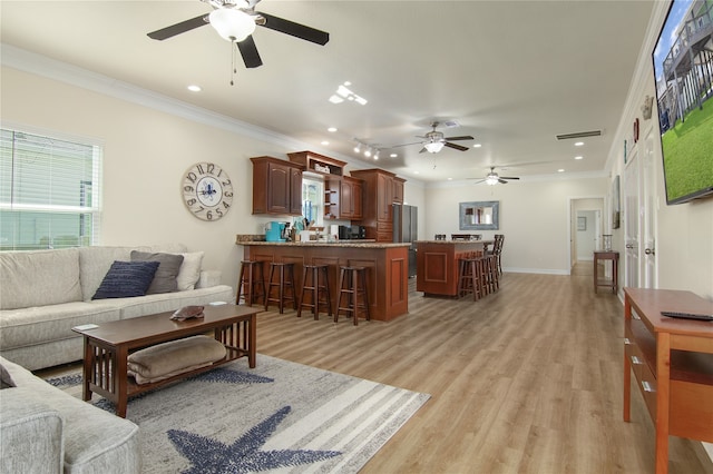 living room with ornamental molding, ceiling fan, and light wood-type flooring