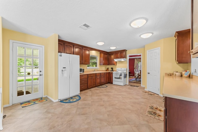 kitchen with under cabinet range hood, white appliances, a sink, visible vents, and light countertops