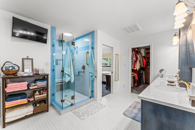 bathroom featuring a shower with door, dual vanity, and tile patterned flooring