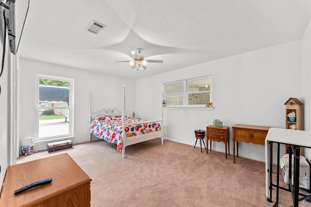 bedroom with carpet floors, ceiling fan, visible vents, and a textured ceiling