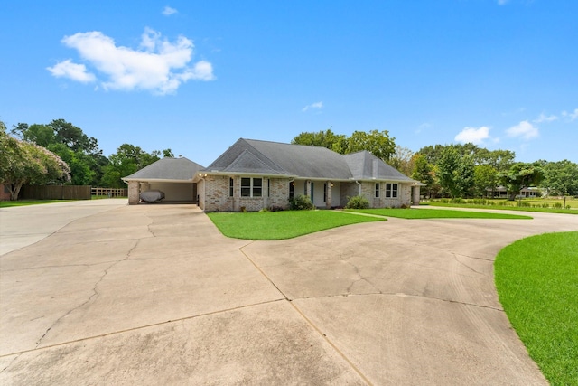 ranch-style home with concrete driveway, brick siding, fence, and a front lawn