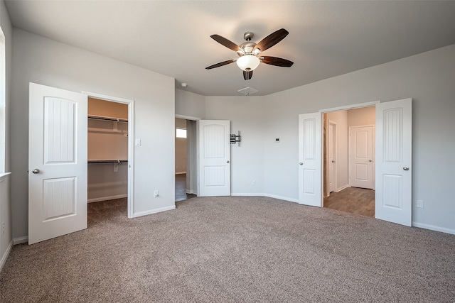 unfurnished bedroom with a closet, carpet flooring, ceiling fan, and a walk in closet