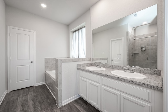 bathroom with double vanity, hardwood / wood-style floors, and separate shower and tub