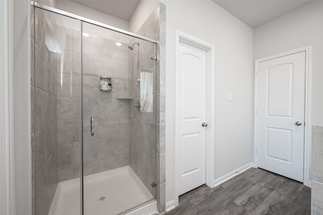 bathroom with a shower with shower door and wood-type flooring