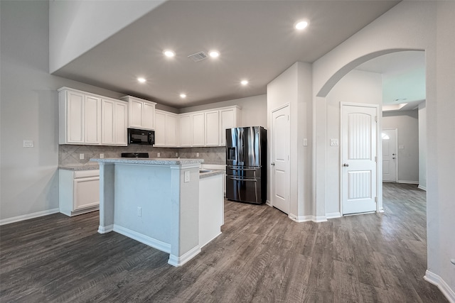 kitchen featuring tasteful backsplash, hardwood / wood-style flooring, white cabinets, a kitchen island, and stainless steel fridge